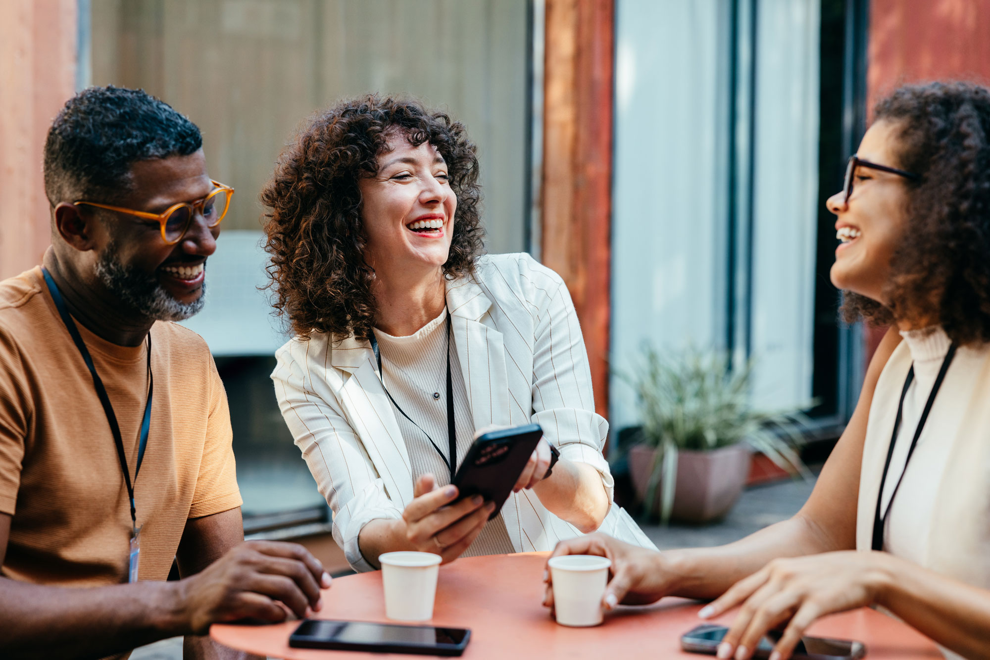 A group of 3 colleagues smiling and chatting while collaborating on a tablet device together